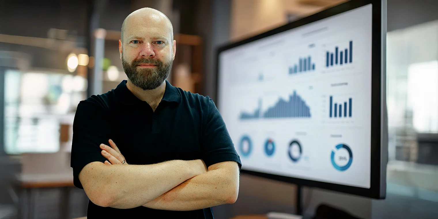 Geschäftsführer Martin Widemann steht auf einem Bild, das die SEA-Leistungen (Search Engine Advertising) der Webagentur Netigo visualisiert; er lächelt in die Kamera, trägt Netigo-Bekleidung und ist vor einem thematisch passenden Hintergrund für digitale Werbung und Online-Kampagnen abgebildet.